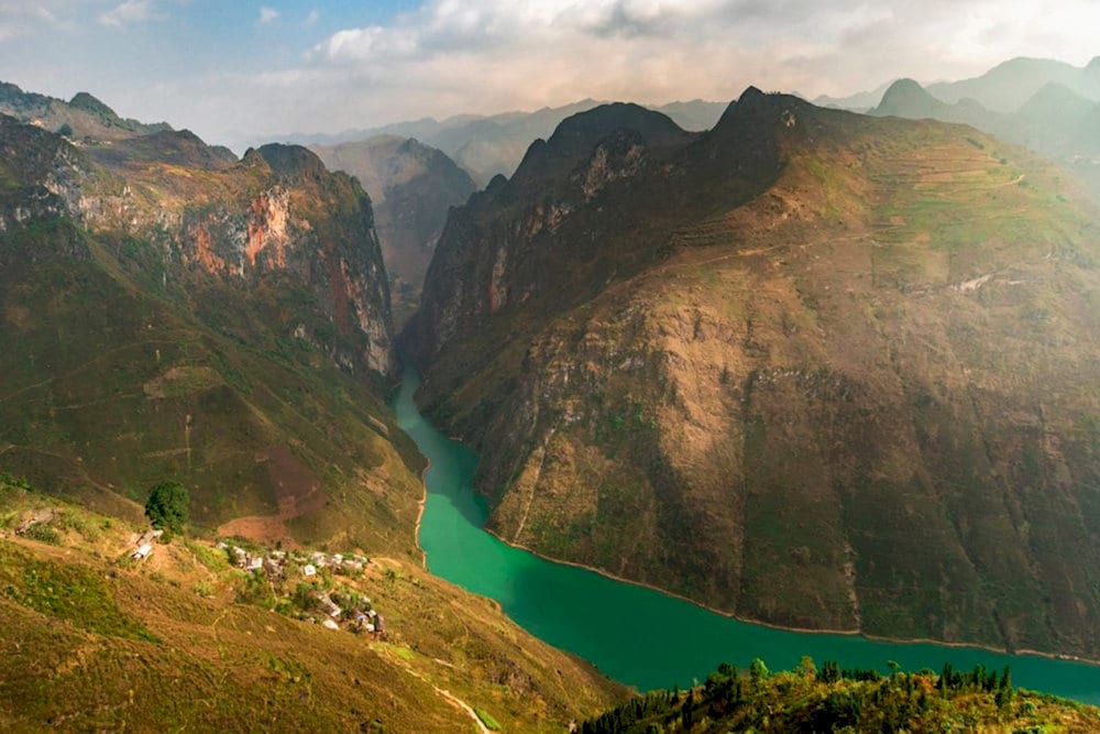 Capture the golden rays illuminating the rugged limestone cliffs from the summit of Ma Pi Leng Pass
